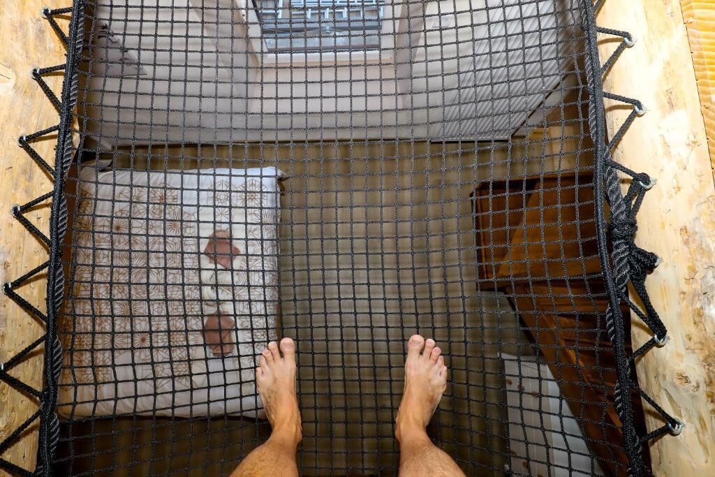 A hammock suspended between two wooden beams with a patterned cushion underneath.