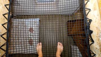 A hammock suspended between two wooden beams with a patterned cushion underneath.