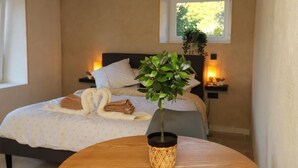 Une chambre à coucher avec un lit, une table de chevet avec une lampe, une fenêtre et une plante en pot.