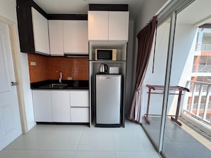 A compact kitchen with white cabinets, a microwave, and a refrigerator. - Bright Corner Pool-view Studio With Balcony - New Nordic VIP 3, Pratumnak (Pattaya)