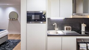Eine moderne Küche mit integriertem Mikrowellenherd, einer Edelstahl-Spüle und einer schwarzen Arbeitsplatte.