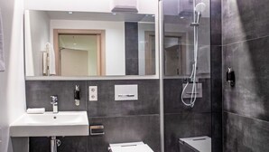 Ein modernes Badezimmer mit Waschbecken, Toilette und einer Duschkabine.