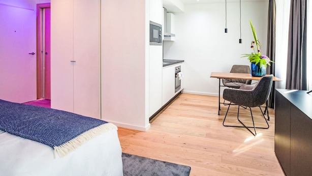 Ein modernes Hotelzimmer mit Bett, Schreibtisch und einer Küchenzeile.