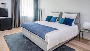 Ein modernes Schlafzimmer mit einem großen Bett, einem Flachbildfernseher und einem Kleiderschrank.