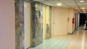 A corridor with marble walls, a tiled floor, and a fire extinguisher on the wall. - Indra Hotel Hatyai (Hat Yai)