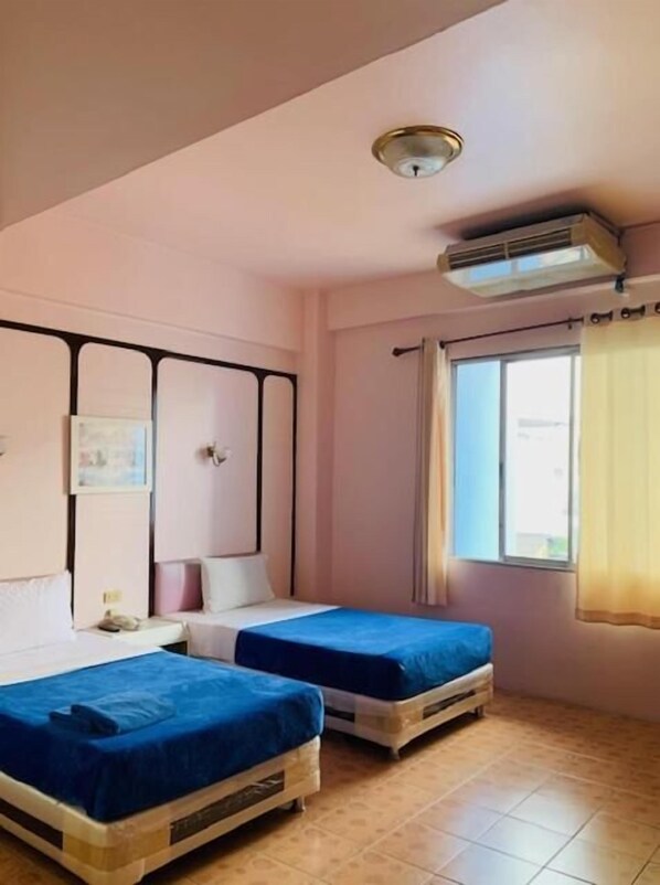Habitación con dos camas, ventilador de techo, aire acondicionado y una ventana con cortinas.