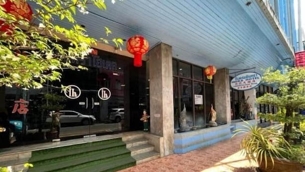 A hotel entrance with a signboard, a staircase leading to the entrance, and a potted plant on the right. - Indra Hotel Hatyai (Hat Yai)