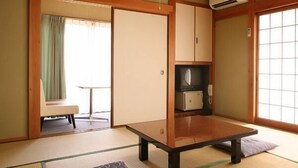 Perinteinen japanilainen huone, jossa on tatamimatto, matala pöytä, liukuovet ja pieni keittokomero.