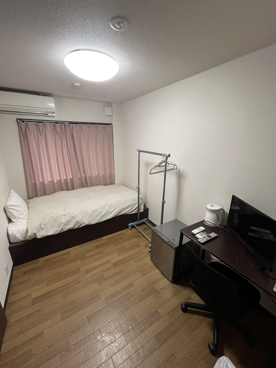 A hotel room with a bed, a desk with a computer, a coffee maker, and a TV.