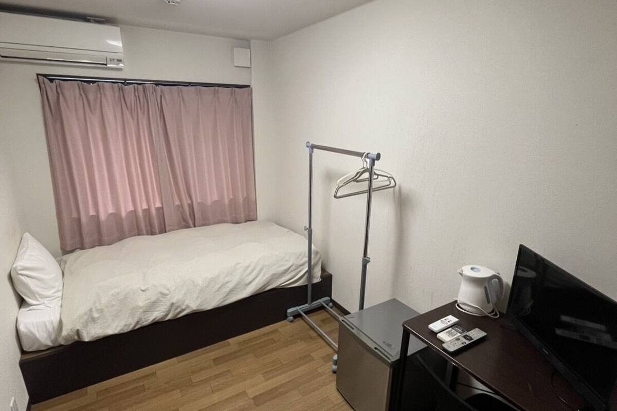 A hotel room with a bed, a desk with a computer, a coffee maker, and a TV.
