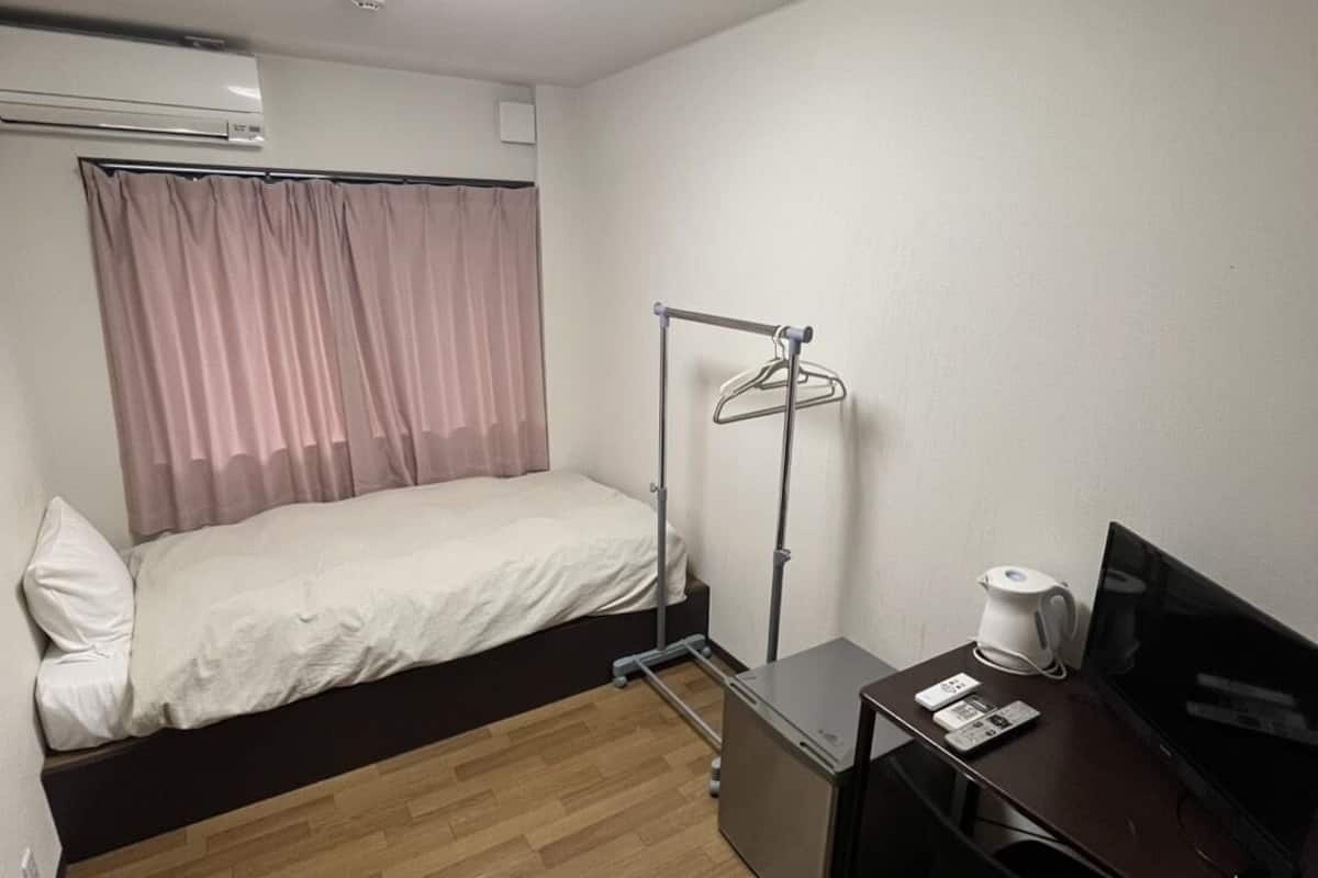 A hotel room with a bed, a desk with a computer, a coffee maker, and a TV.