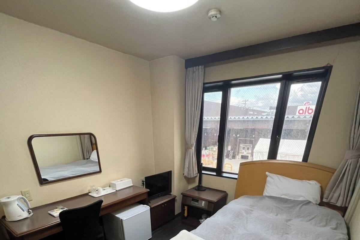 A hotel room with a bed, desk, chair, and a window with a view.
