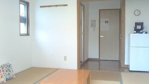 Une pièce comprenant une table en bois, un réfrigérateur, une horloge et une porte donnant sur une autre pièce.