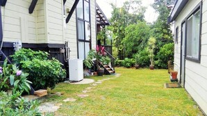 A residential property with a well-maintained lawn, a stone pathway, and various potted plants. - Cottage Forest Paradiso (Onna)