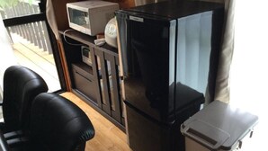 A compact kitchenette with a microwave, a small refrigerator, and a trash bin. - Cottage Forest Paradiso (Onna)