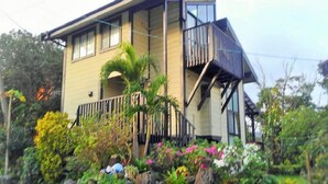 A two-story house with a balcony, surrounded by a garden with various plants and flowers. - Cottage Forest Paradiso (Onna)