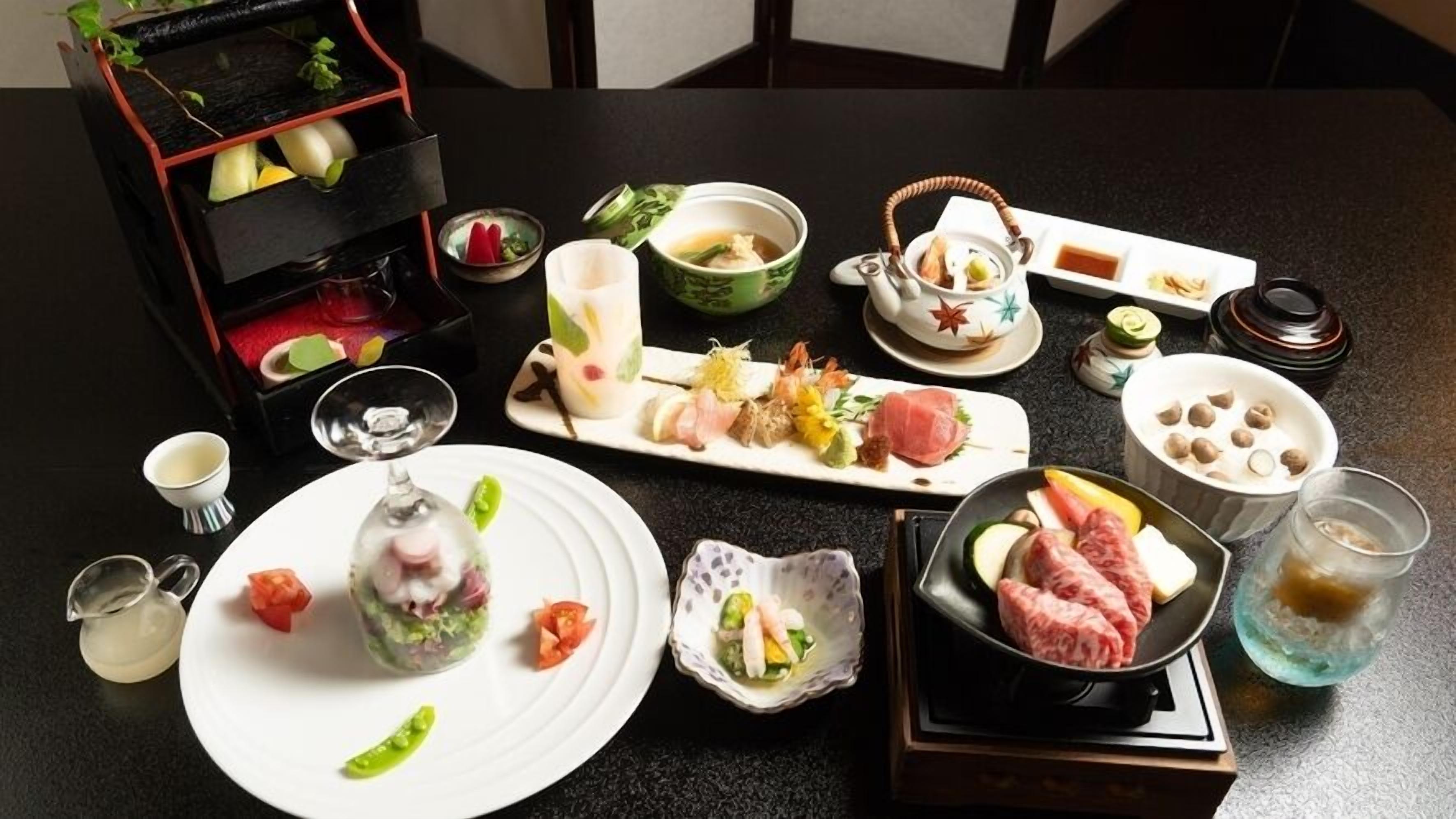 A dining table with various dishes, including sushi, sashimi, and a teapot.