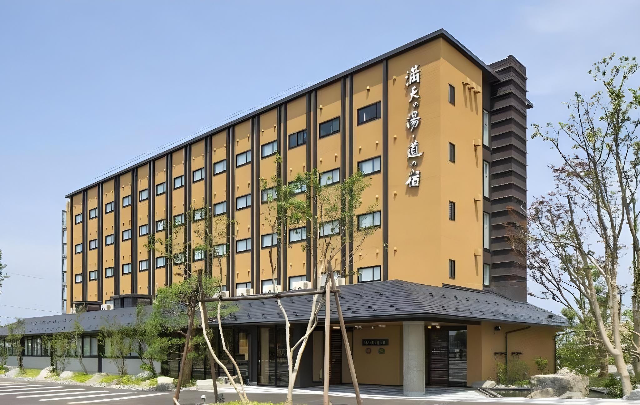 A multi-story hotel with a yellow facade, a covered entrance, and a clear sky.