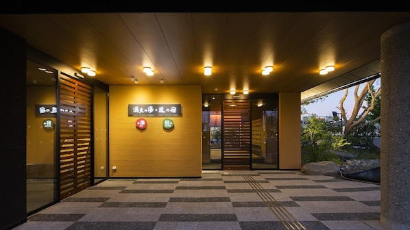 L’entrée d’un hôtel, avec un sol à carreaux, un comptoir de réception et des panneaux indiquant l’emplacement du spa et des services offerts par l’hôtel.