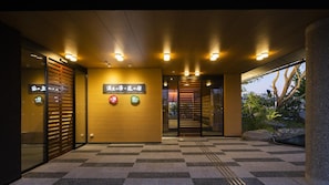 A hotel entrance with a checkered floor, a reception desk, and signs indicating a spa and hotel services.