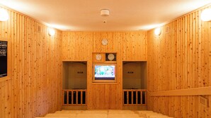 Een sauna met houten wanden, een televisie en bankjes.