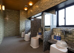 Des toilettes comprenant plusieurs urinoirs, un lavabo et un miroir.
