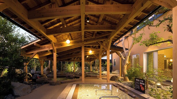 A traditional Japanese onsen with a wooden structure, a tiled hot spring area, and surrounding rocks and plants. - Manten no Yu Michi no Yado (Hakusan)