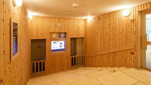 Interior de fusta amb una escala, un rellotge i una pantalla de televisió.