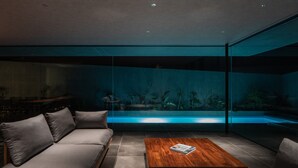 Un salon moderne avec un aquarium intégré dans un mur en verre, un canapé et une table basse.
