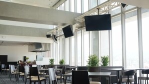 Un vaste espace de restauration intérieur doté de grandes fenêtres, de nombreuses tables et chaises, et d’un design moderne.