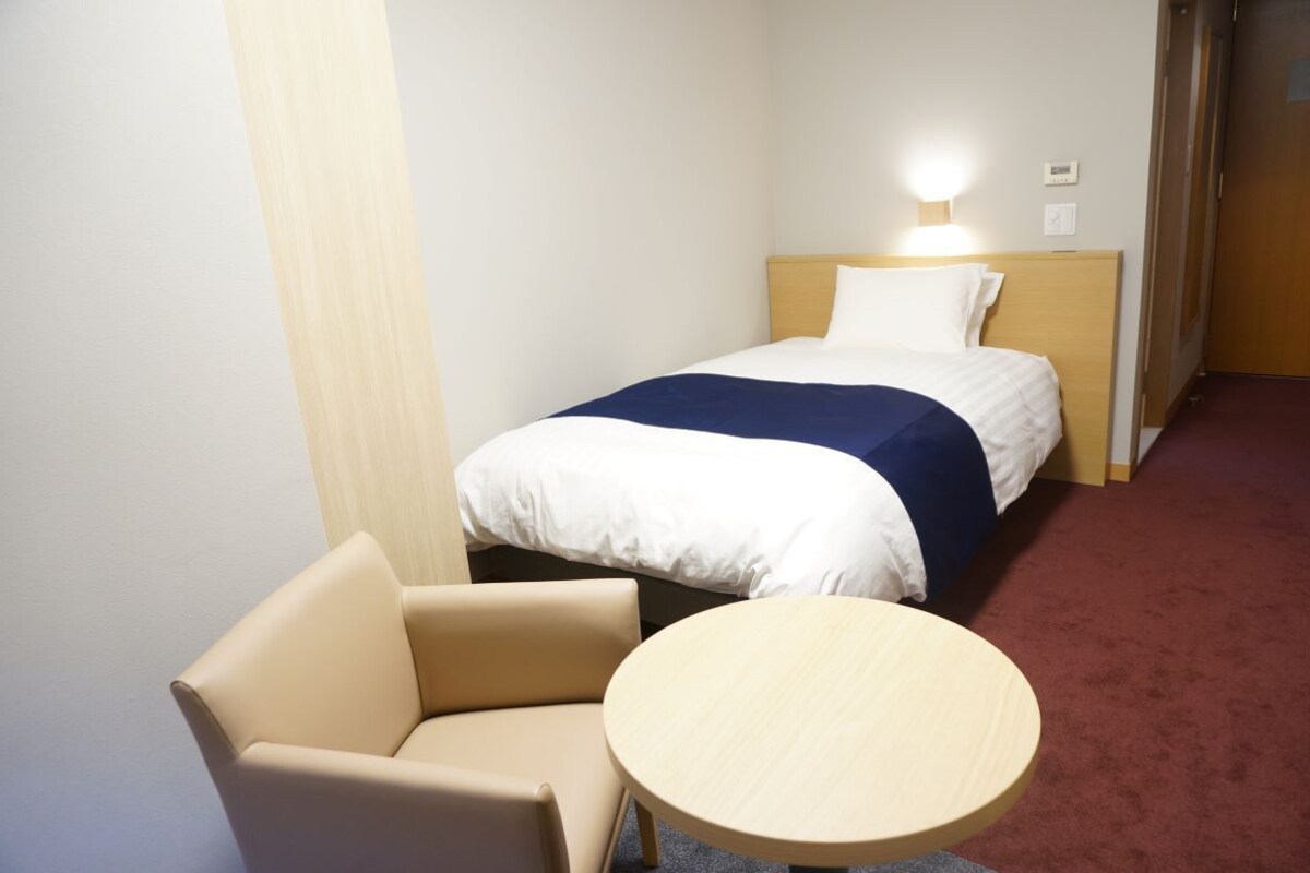 Ein Hotelzimmer mit einem Bett, einem Sessel und einem kleinen Rundtisch.