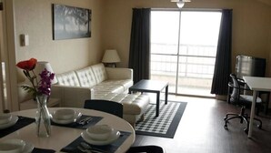 A hotel room with a dining table set for four, a sofa, a small table, and a desk with a chair. - Seaviewcourt Kobe (Kobe)