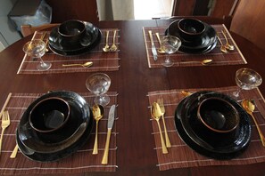A dining table set with black plates, gold cutlery, and clear wine glasses. - Seaviewcourt Kobe (Kobe)