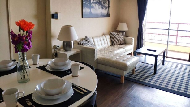 A modern living room with a sofa, dining table, and a view through a large window. - Seaviewcourt Kobe (Kobe)
