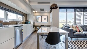 Una cocina moderna con lavavajillas, una mesa de comedor con sillas y un sofá de cuero negro con cojines.