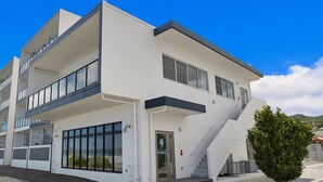 Un edificio moderno de dos pisos con techo plano, ventanas amplias y una escalera que conduce al nivel superior.