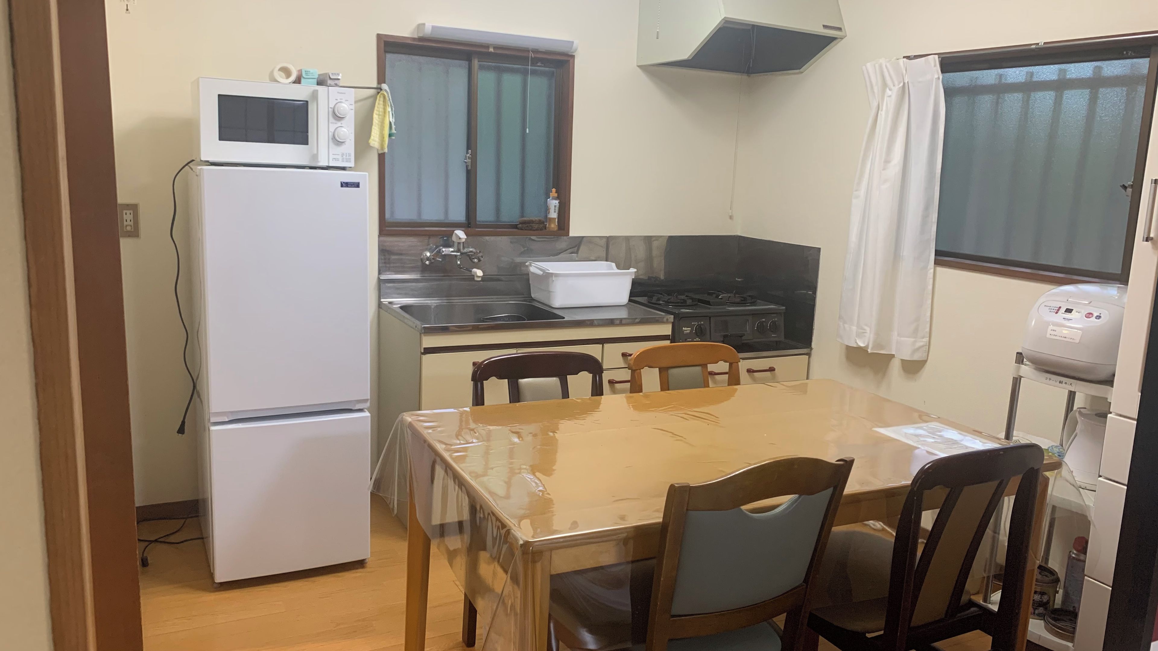A compact kitchen with a refrigerator, microwave, stove, sink, and a dining table with chairs.