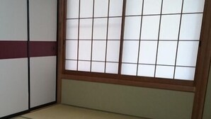 Une pièce de style japonais traditionnel, avec un sol recouvert de tatamis, des paravents en papier de riz (shoji) et une porte basse en bois.