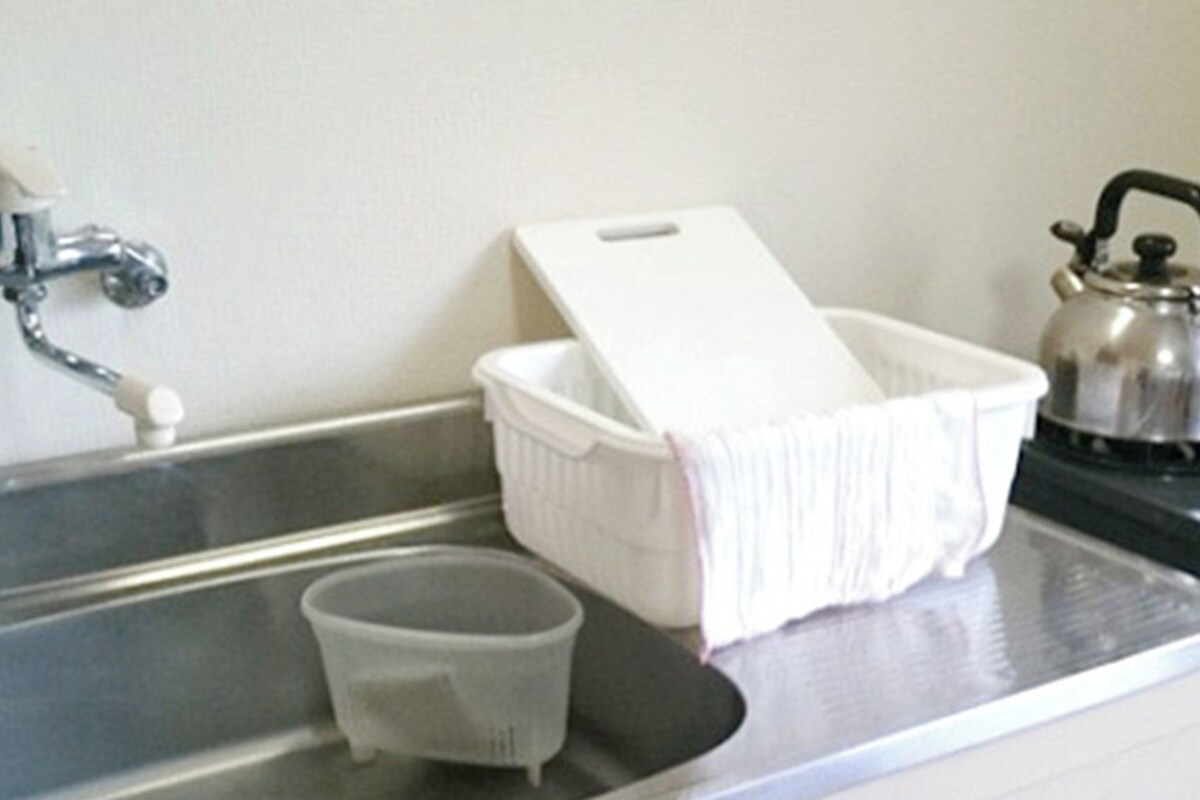 Un évier de cuisine avec une bouilloire, un bac blanc et une tasse.