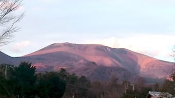 A mountain with a gentle slope and a flat summit, surrounded by trees and a few buildings.