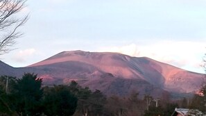 Una montaña de pendiente suave y cima plana, rodeada de árboles y algunos edificios.