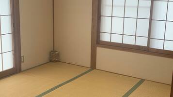 A traditional Japanese room with tatami flooring, shoji screens, and a sliding door.