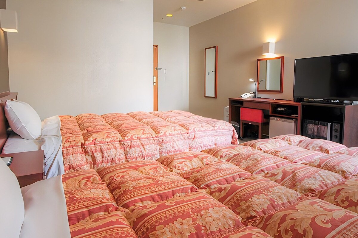 Una habitación de hotel con una cama grande, un escritorio, un televisor y un espejo.