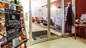 Entrada de hotel con puerta de cristal, mostrador de recepción y exhibición de folletos.
