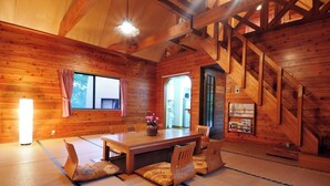 Un intérieur en bois comprenant un coin repas, des tatamis et un escalier.