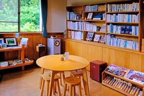 Eine Bibliothek mit Holzbögen, einem runden Tisch mit Stühlen und einer kleinen Kommode.