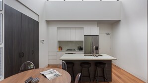Een moderne keuken met een centraal eiland, witte kasten en een roestvrijstalen koelkast.