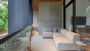 Een moderne woonkamer met een modulaire bank, een glazen tafel en een groot raam.