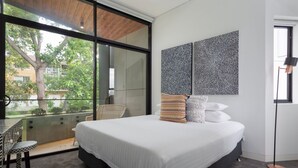 Een moderne slaapkamer met een groot bed, uitzicht op de omgeving en een eethoek met een tafel en stoelen.