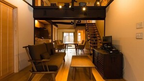 Un ambiente compatto con divano, tavolo da pranzo e una scala che conduce a un piano superiore.